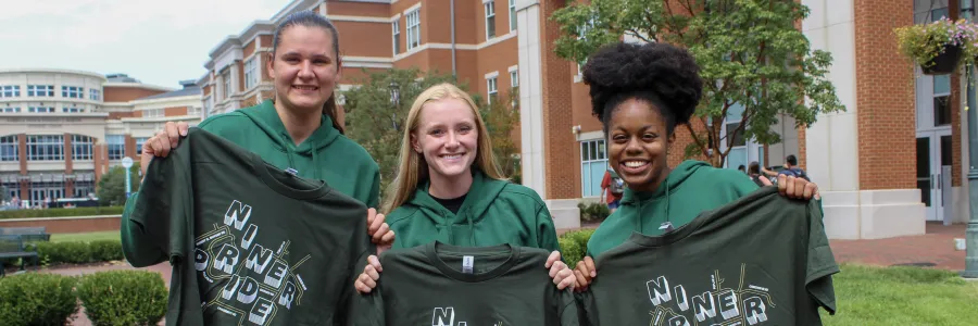 Students smiling and holding their Gold Rush shirts in the CHHS/CoEd Plaza