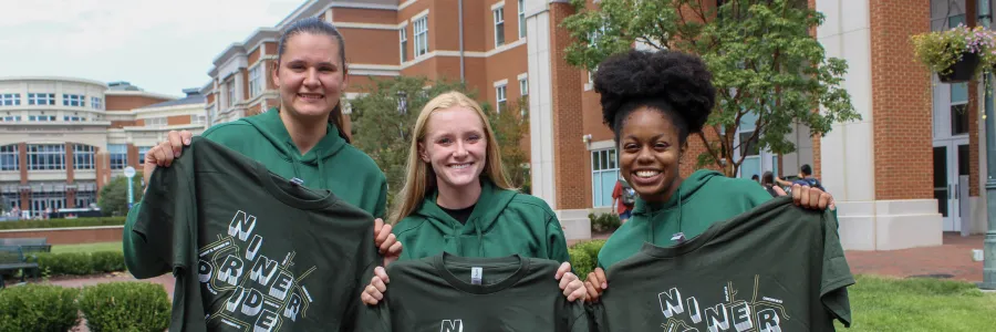 Students smiling and holding their Gold Rush shirts in the CHHS/CoEd Plaza