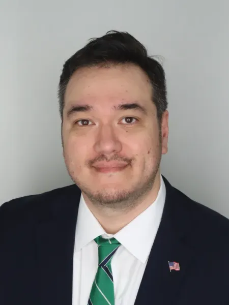 Chris Brasel smiling in a black suit and green tie