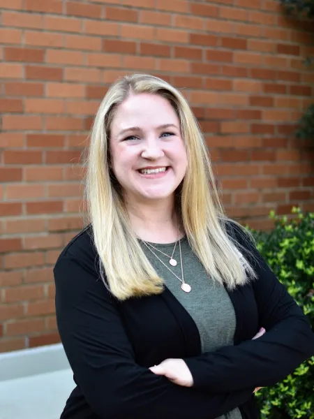 Sarah Simard smiling in front of a brick wall