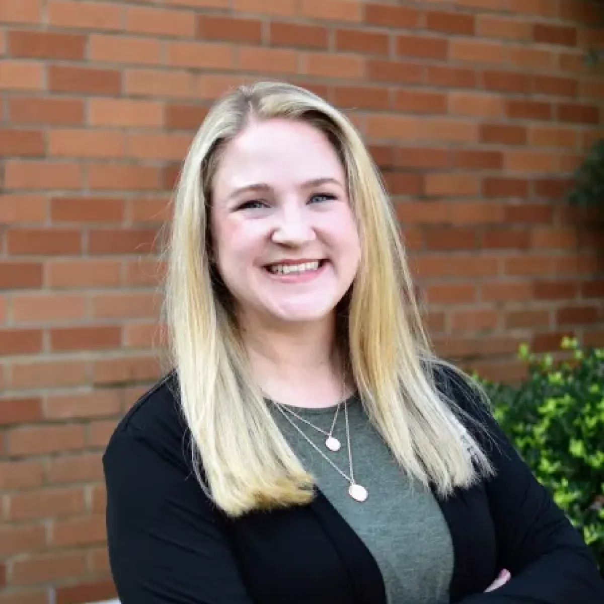 Sarah Simard smiling in front of a brick wall